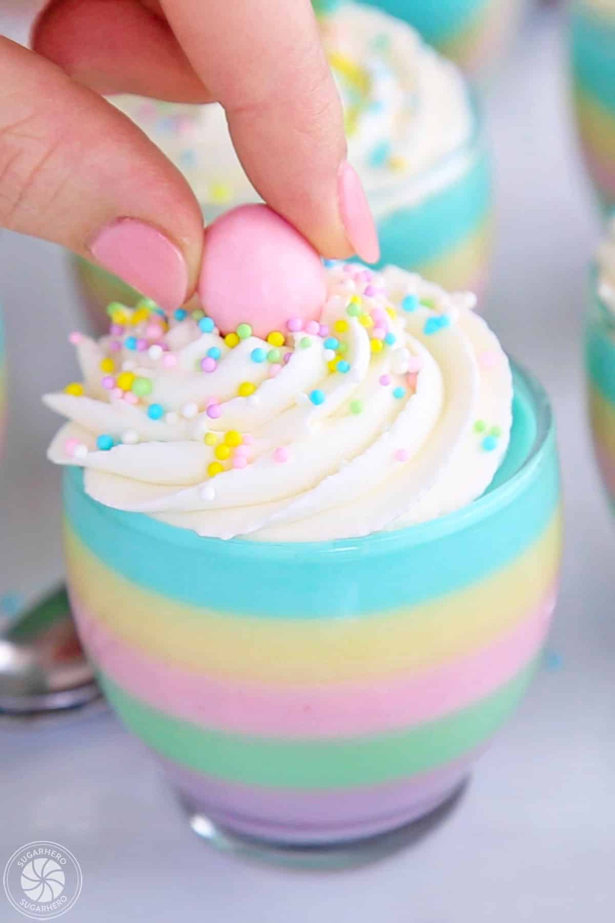 Hand placing a candy egg on top of a gelatin cup.