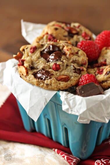 Close up of Raspberry Almond Chocolate Chunk Cookies in a light blue ceramic container.