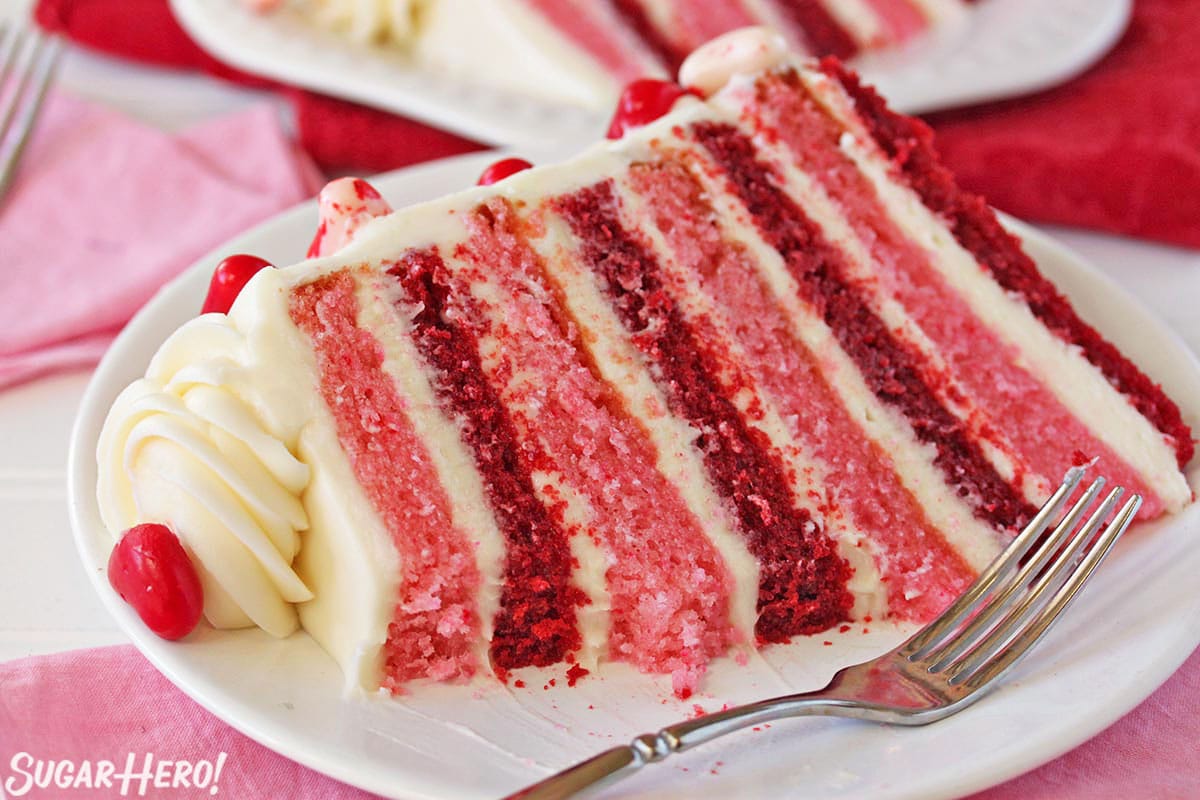 Close-up of slice of pink and red velvet cake on a white plate, with several bites taken out.