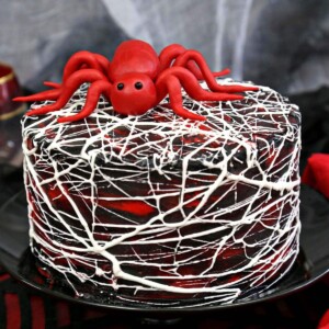 Close up of Red Velvet Marshmallow Spiderweb Cake on a black cake stand.
