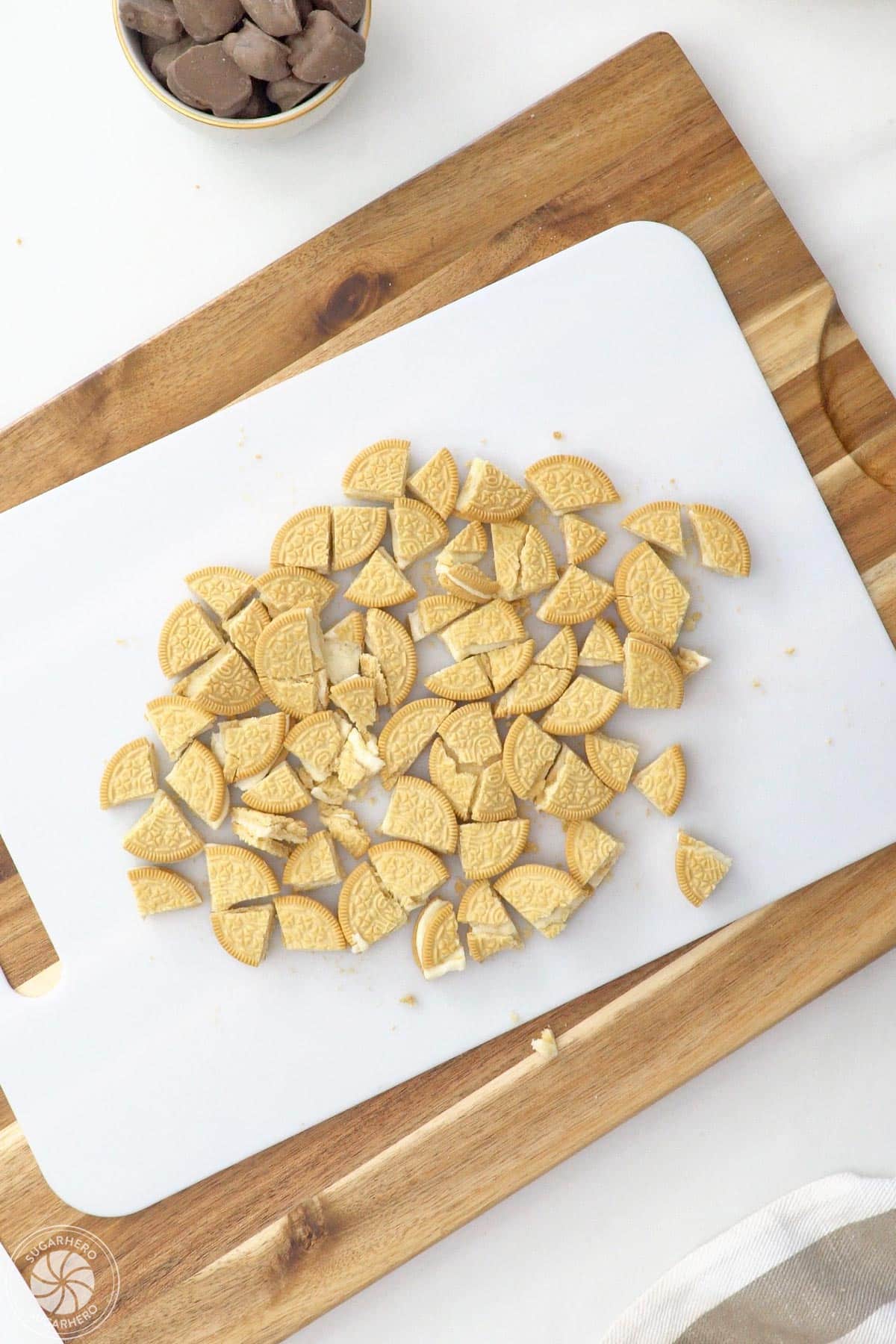 Chopped vanilla sandwich cookies on a white cutting board.
