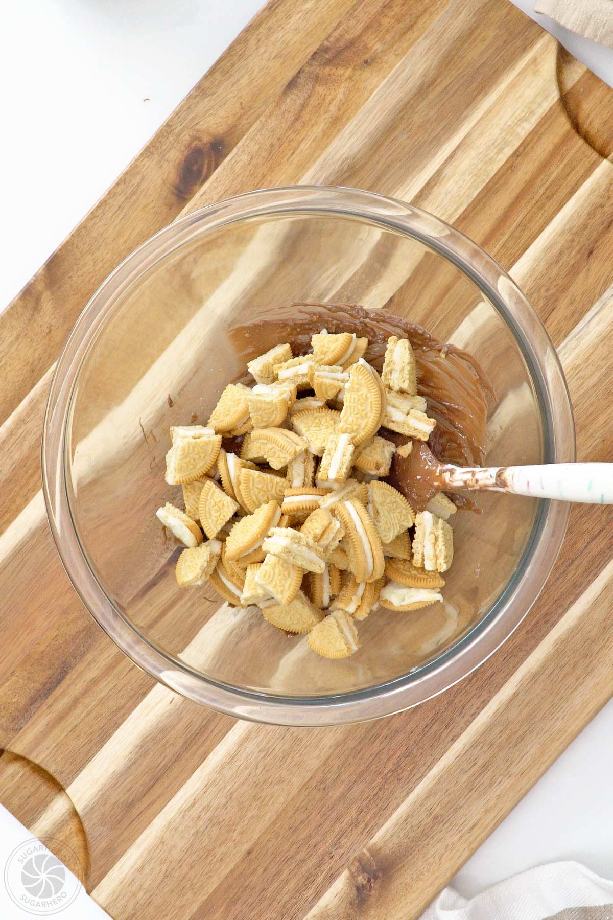 Chopped cookies on top of melted coating and popping candy in a glass bowl.