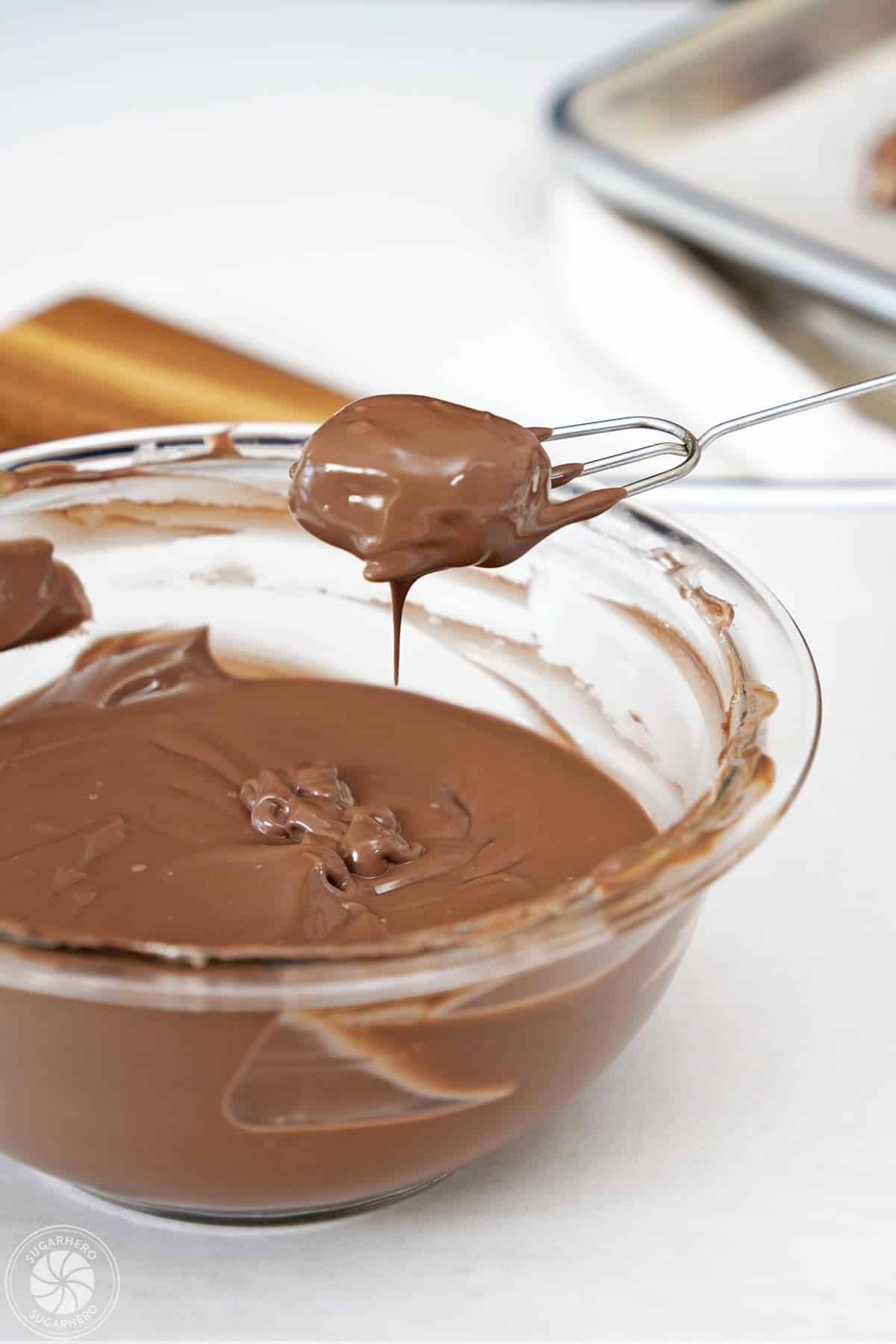 Dipping a Root Beer Float piece in melted candy coating.