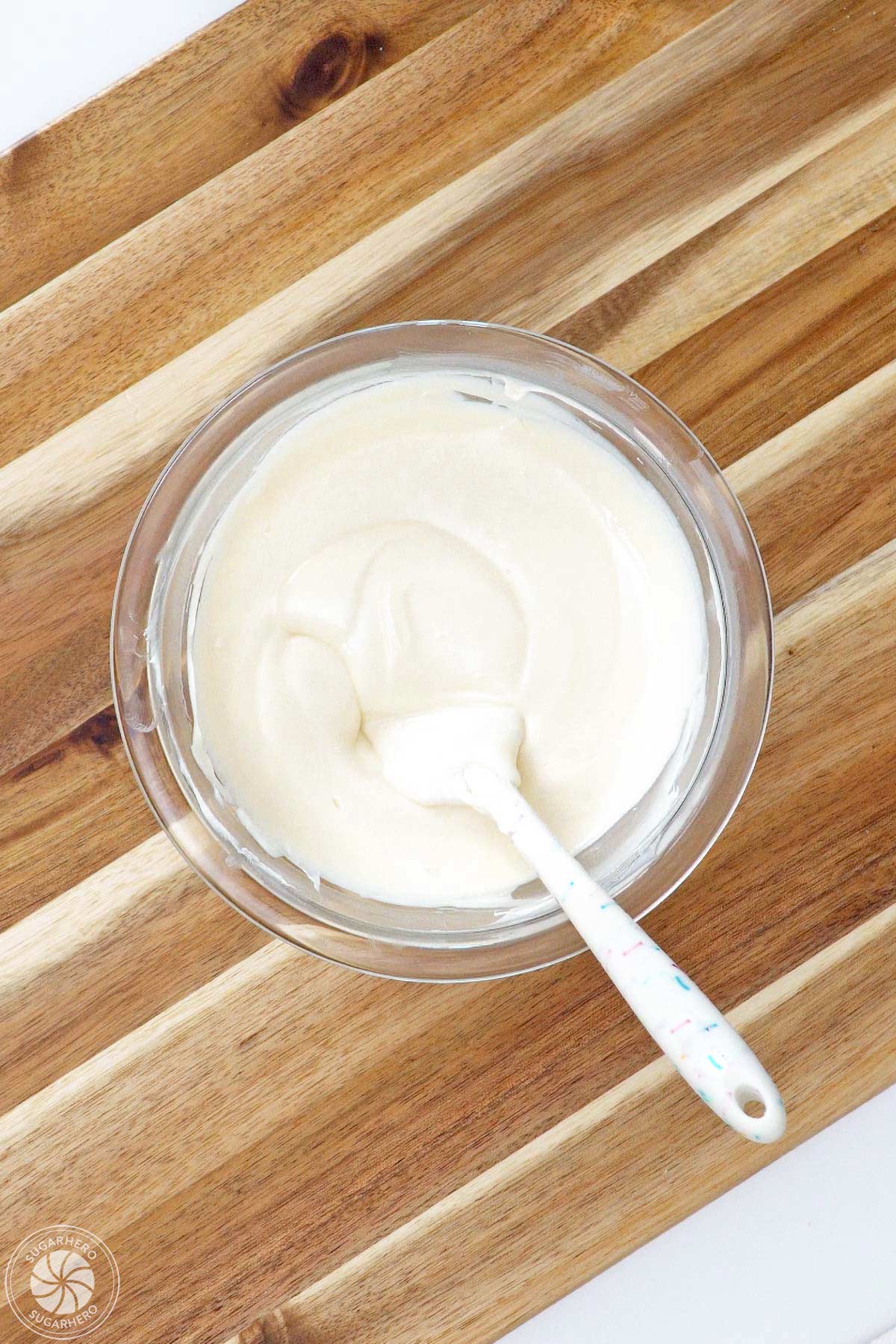 Bowl of melted white candy coating on a wooden cutting board.