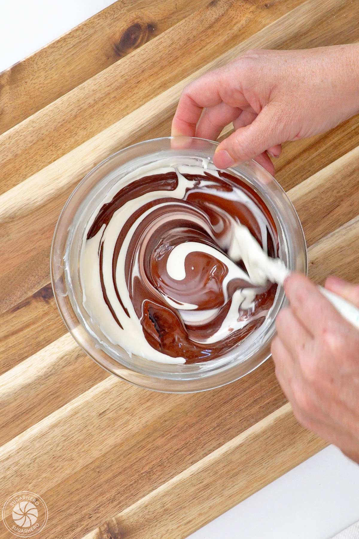 Stirring brown coloring into a bowl of melted white candy coating.