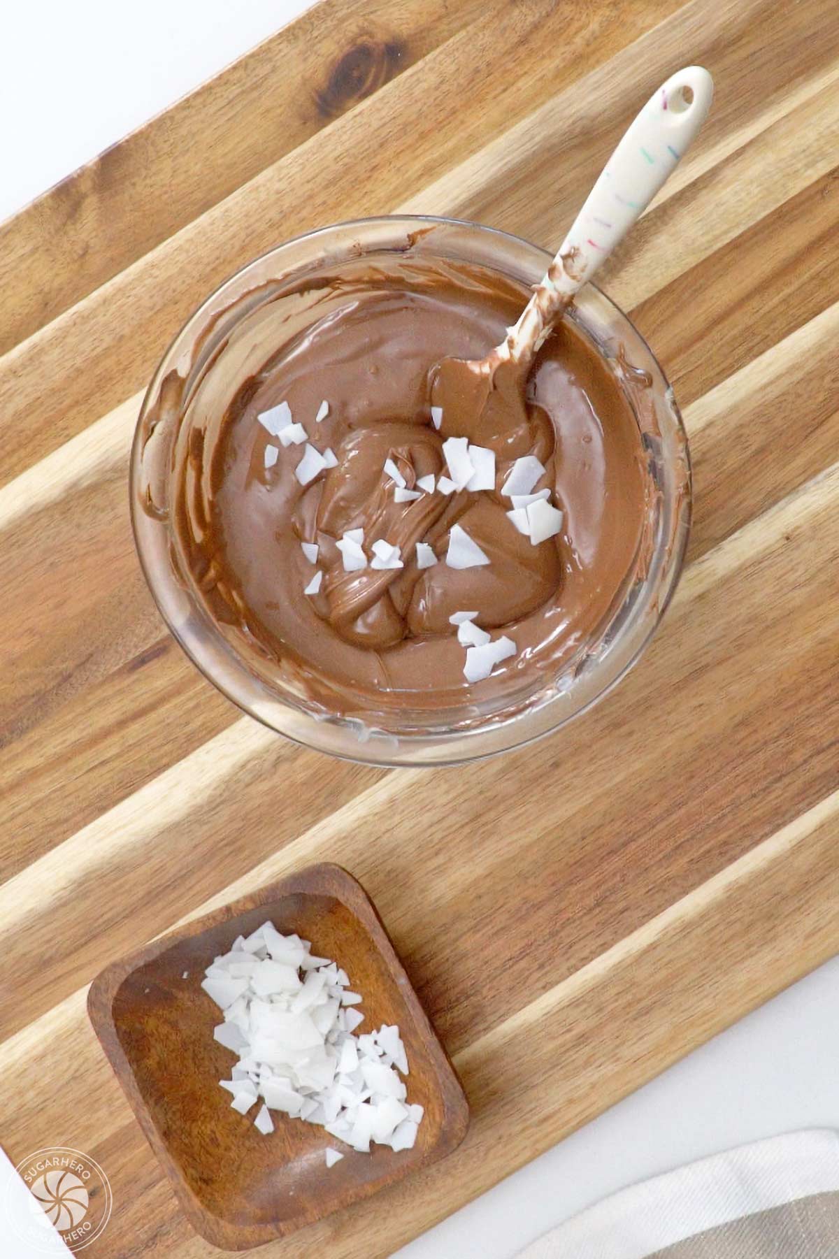 Flakes of paramount crystals on top of a bowl of brown candy coating.
