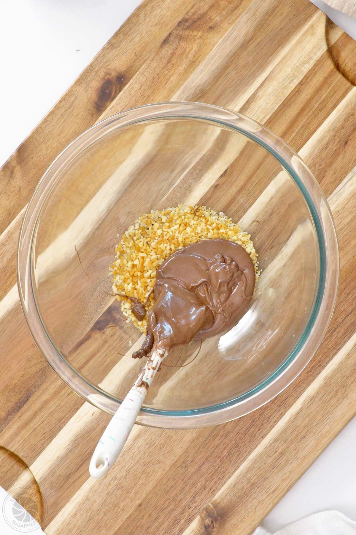 Brown candy coating added to popping candy in a large glass bowl.