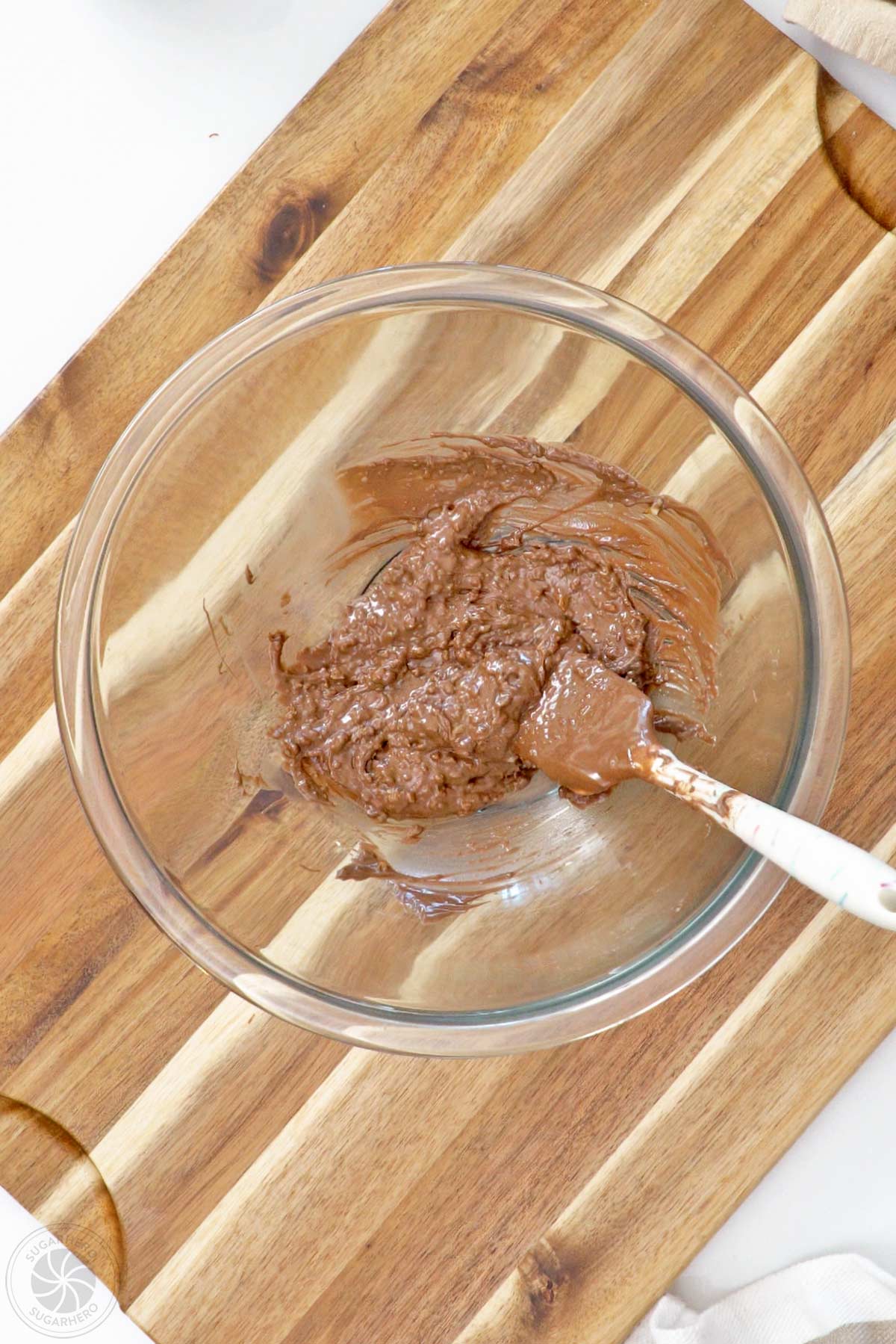 Popping candy and melted candy coating stirred together in a glass bowl.