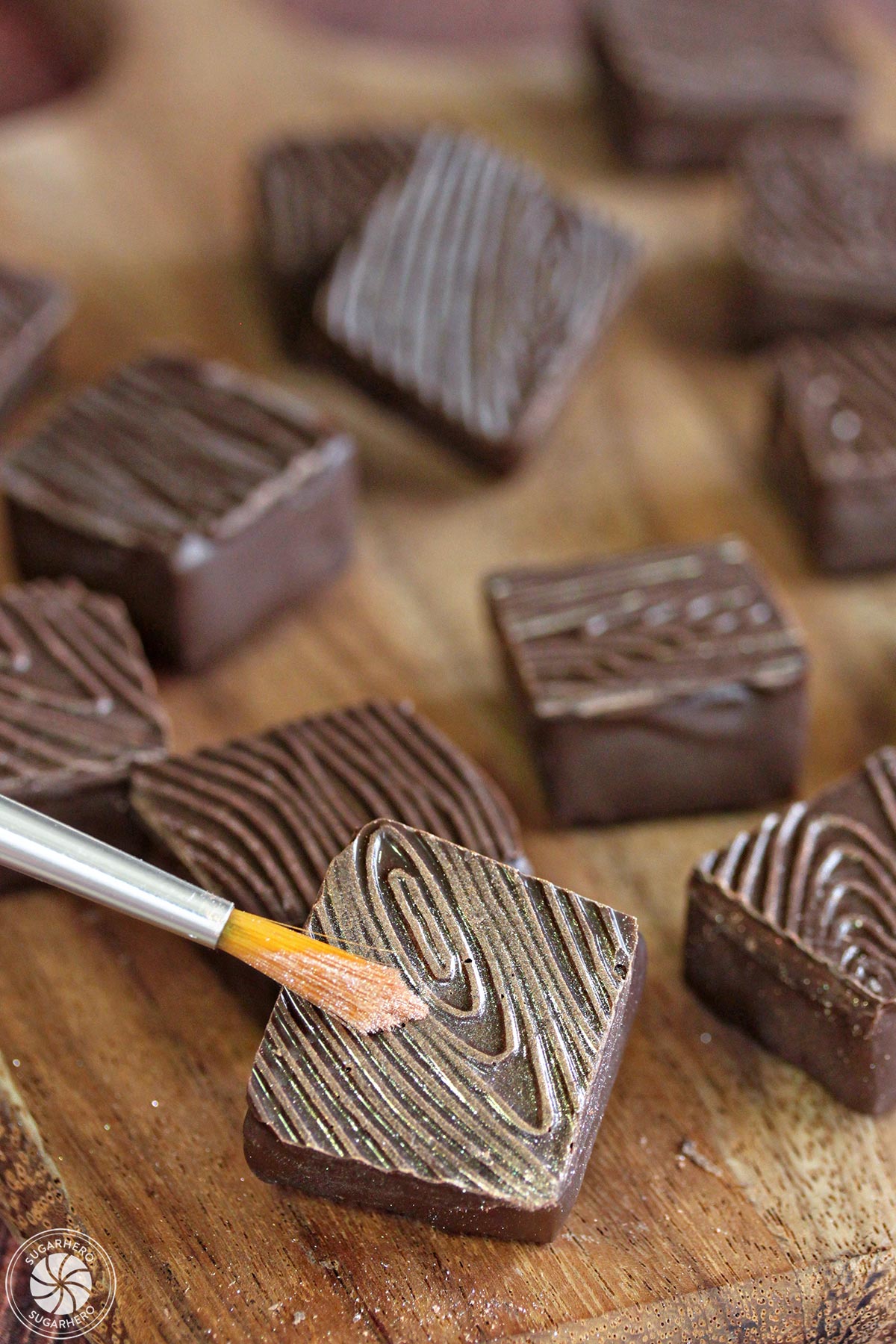 Rosemary Raspberry Truffles - painting gold luster dust on a chocolate truffle with a good grain texture | From SugarHero.com