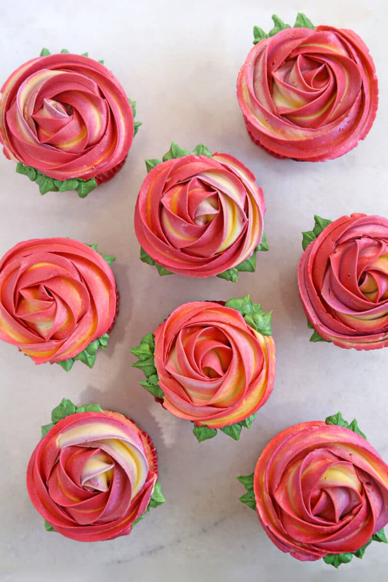Overhead shot of eight Rosette Cupcakes on a white surface.