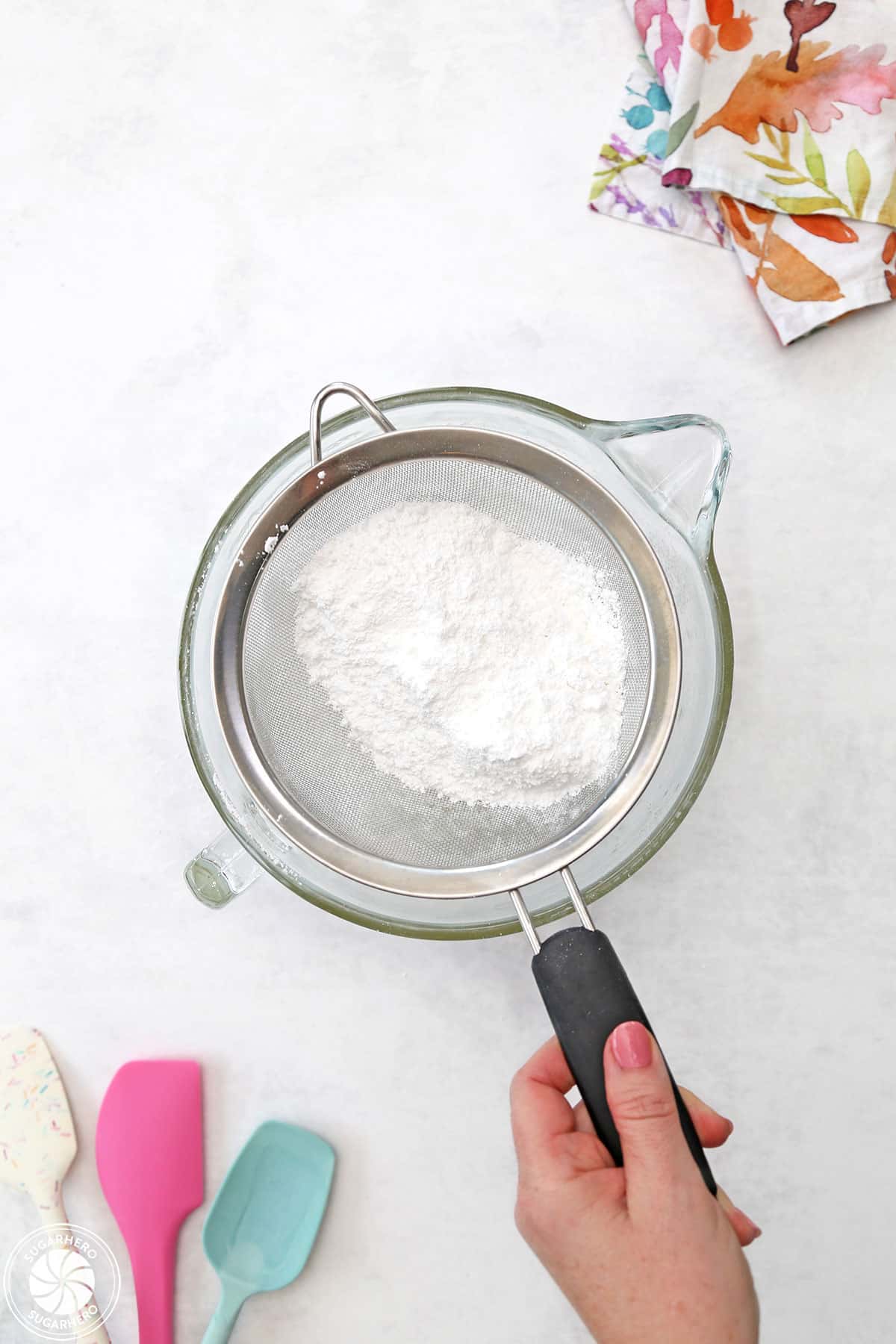 Sifting powdered sugar over a mixing bowl to make royal icing.