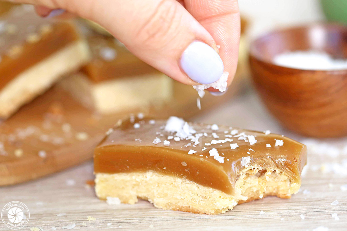 Hand sprinkling flaked sea salt on a Salted Caramel Bar.