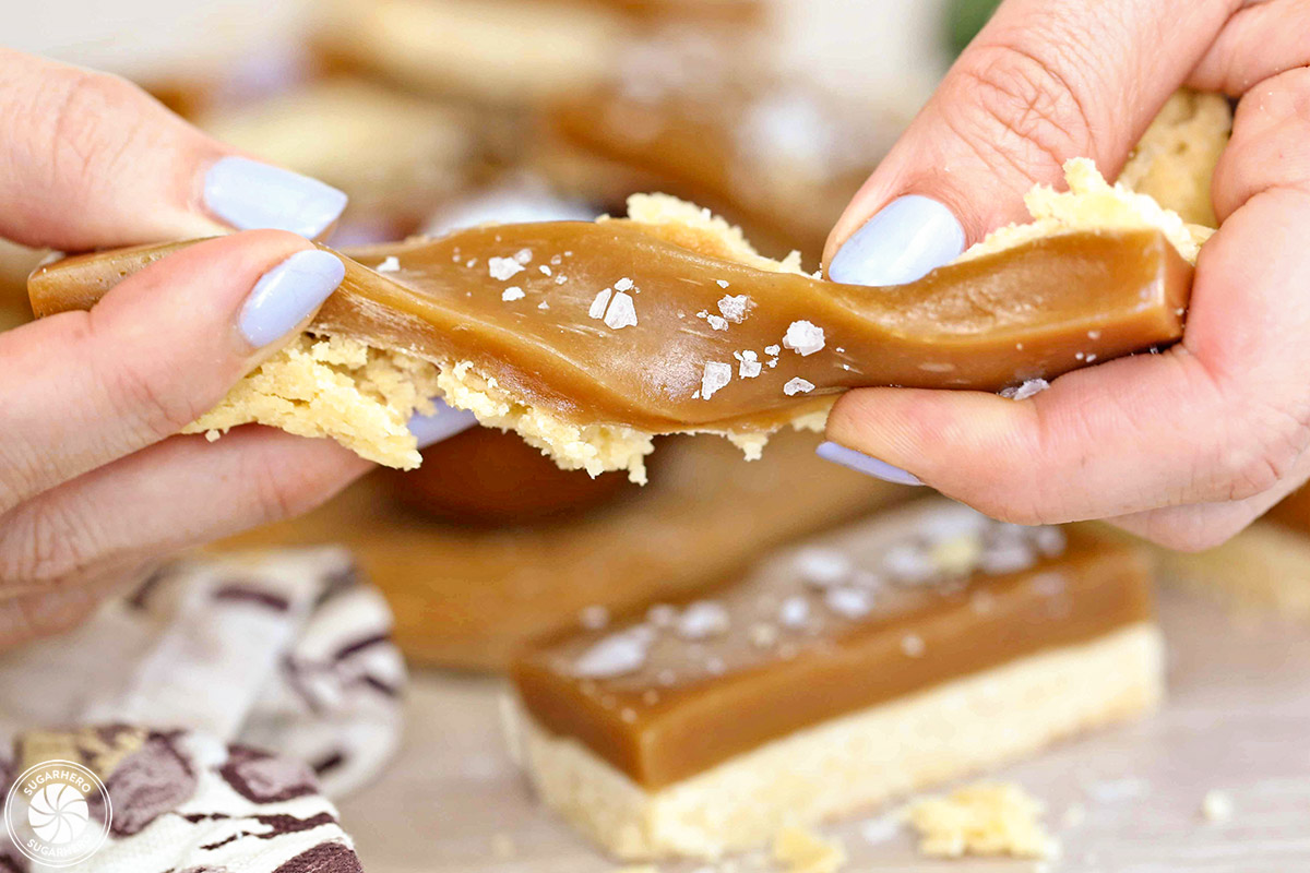 Image of a hand twisting a Salted Caramel Bar to show soft texture.