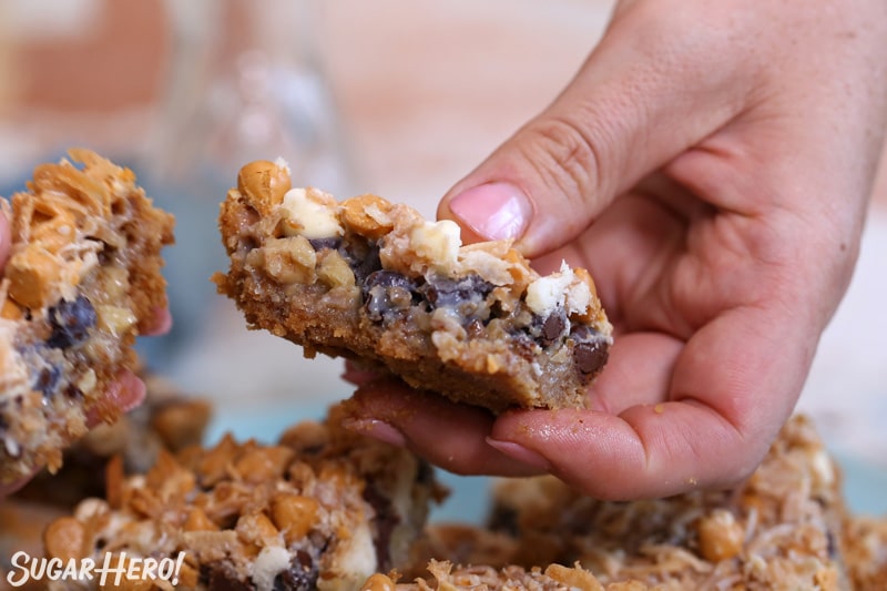 Hand breaking apart a Seven Layer Bar