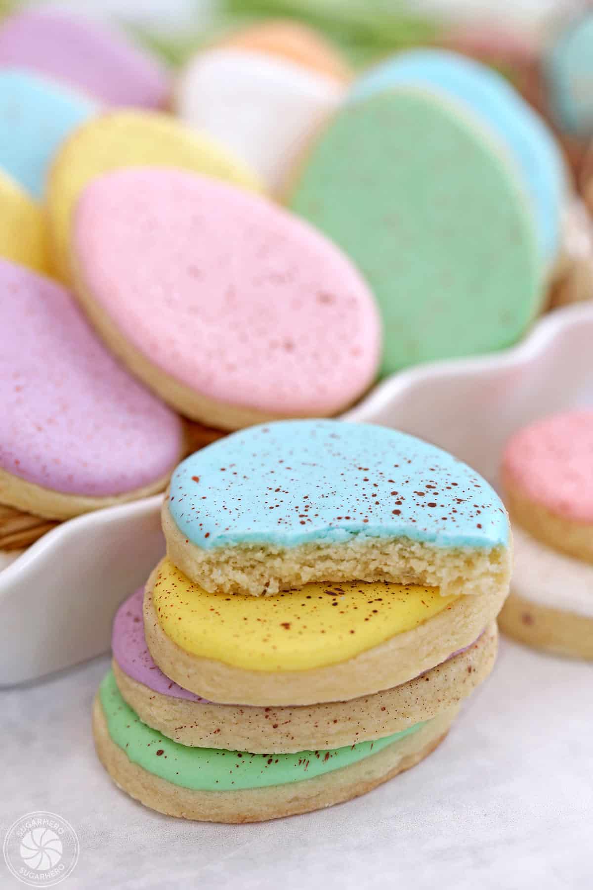 Stack of pastel Speckled Easter Egg Sugar Cookies, and the top cookie has a bite taken out.