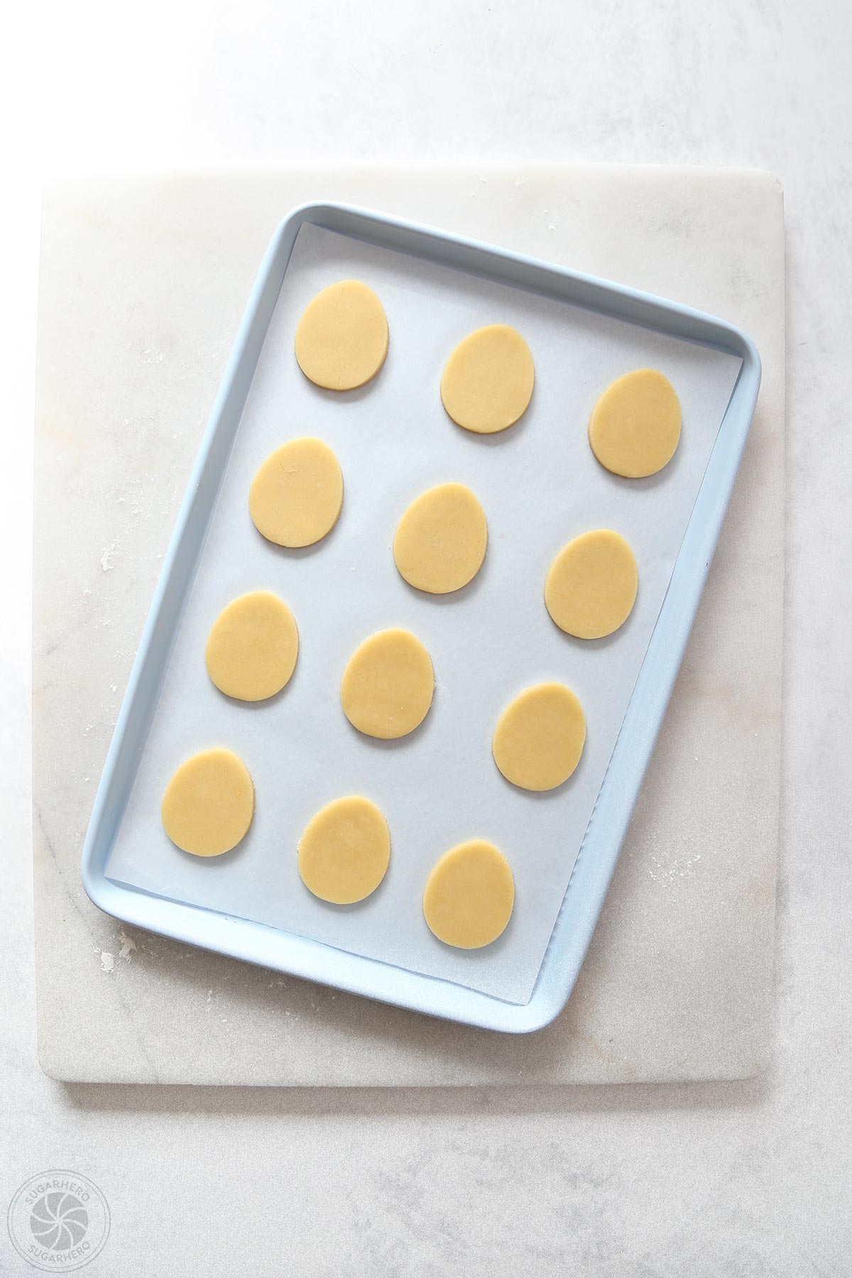 Egg-shaped sugar cookies on a blue baking sheet.