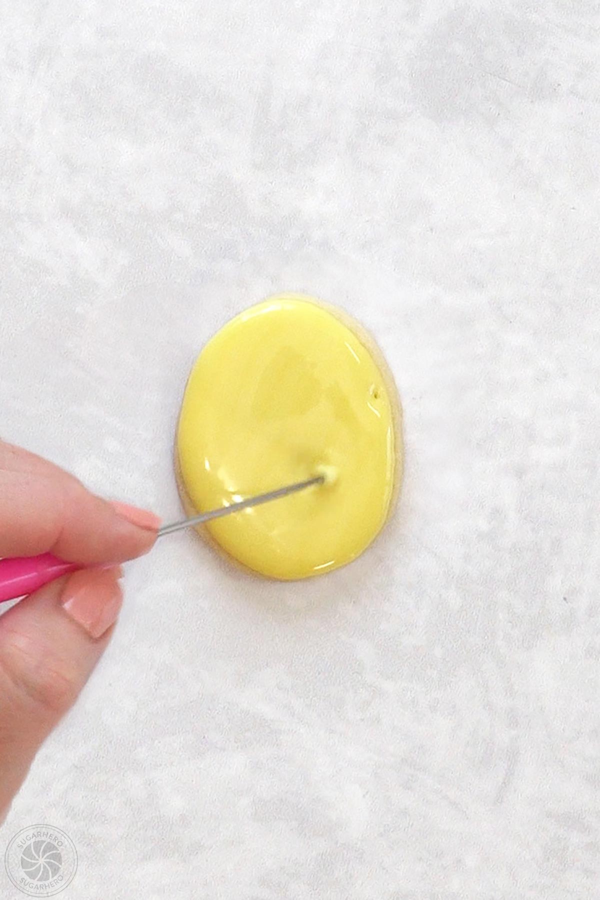 Egg-shaped sugar cookie with a scribe tool evening out the royal icing on top.