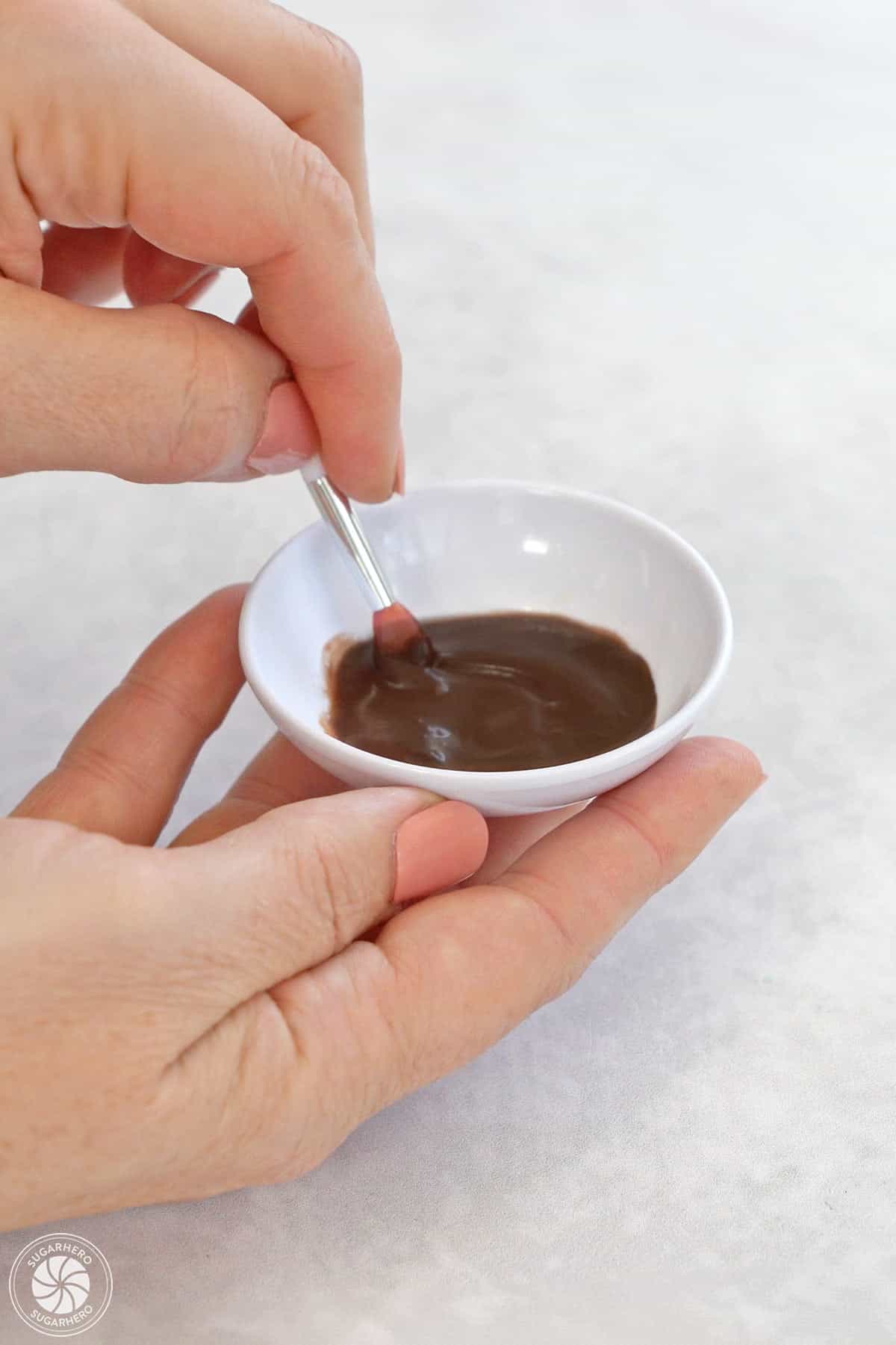Mixing cocoa powder and water in a small white bowl.