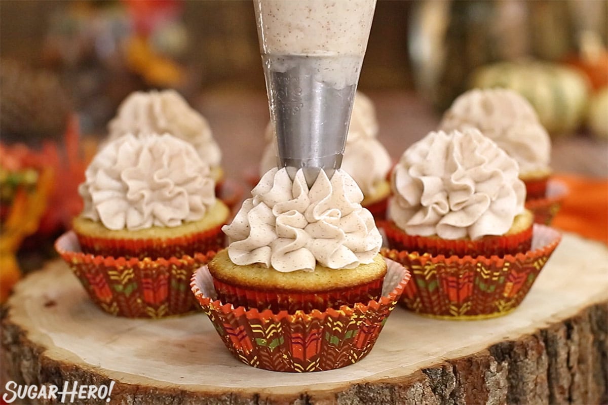 Piping a ruffled swirl of cinnamon buttercream on a spice cupcake.