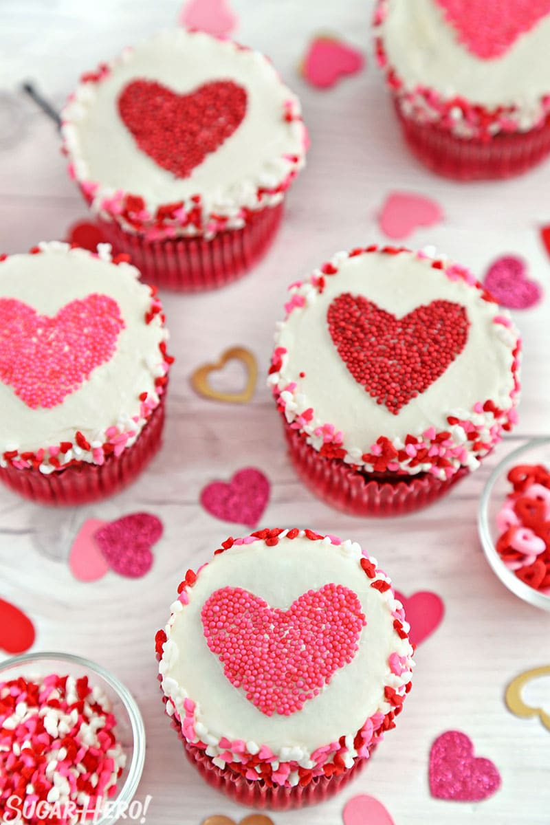 Group of cupcakes with red and pink heart-shaped sprinkle shapes in the center