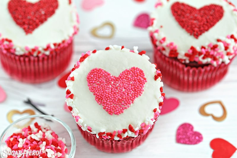 White cupcake with a pink heart-shaped sprinkle shape in the center