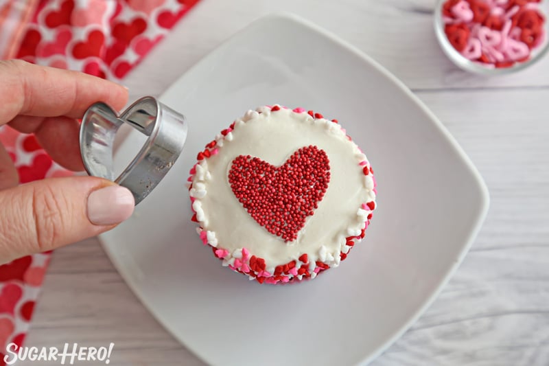 Removing a cookie cutter from the top of a frosted cupcake