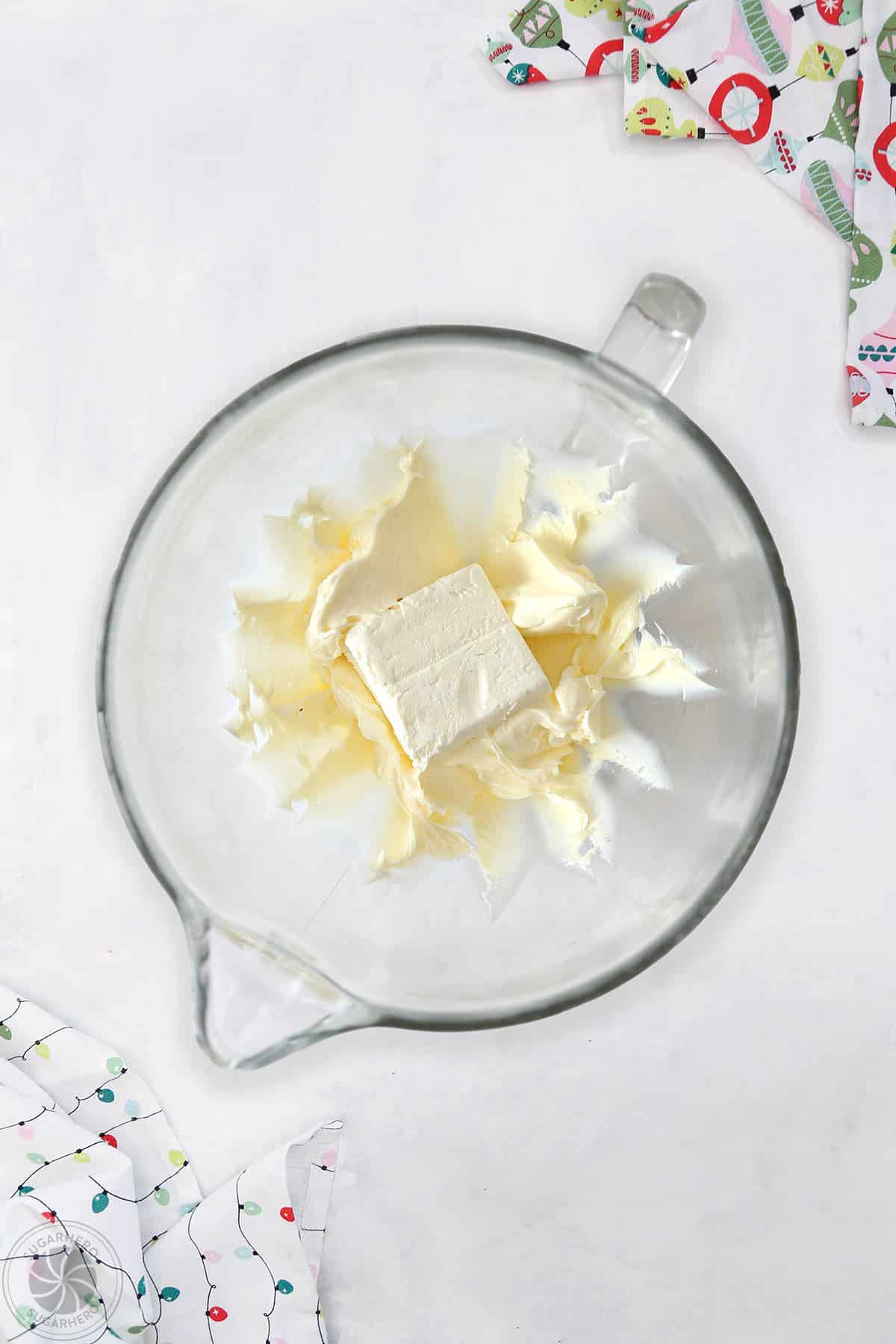 Creamed butter with a block of cream cheese being added to the batter.