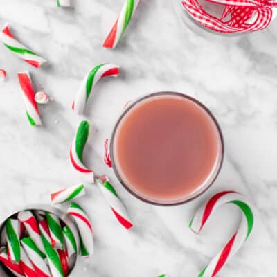 Top view of a jar of peppermint syrup next to broken candy canes.