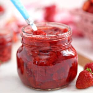Jar of Strawberry Sauce with fresh strawberries to the side.
