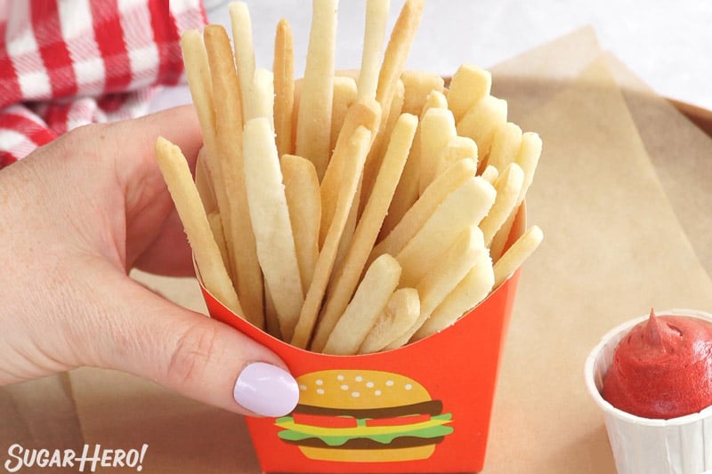 Hand holding a paper cup full of sugar cookie french fries