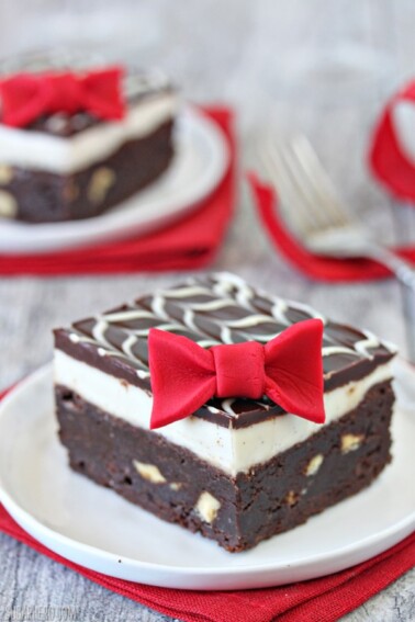 1 Tuxedo Brownie on a small white plate on top of a red napkin.