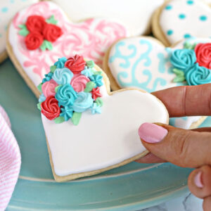 Hand holding a Valentine's Day Sugar Cookie with roses on it.