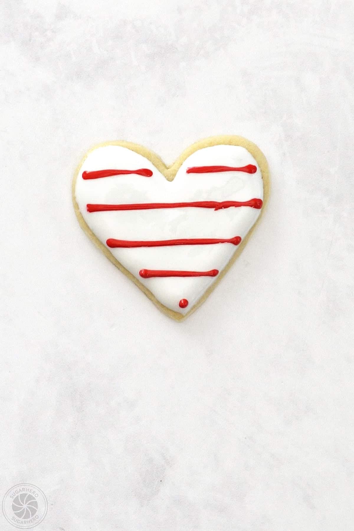 Valentine's Day Sugar Cookie with horizontal lines of red royal icing.