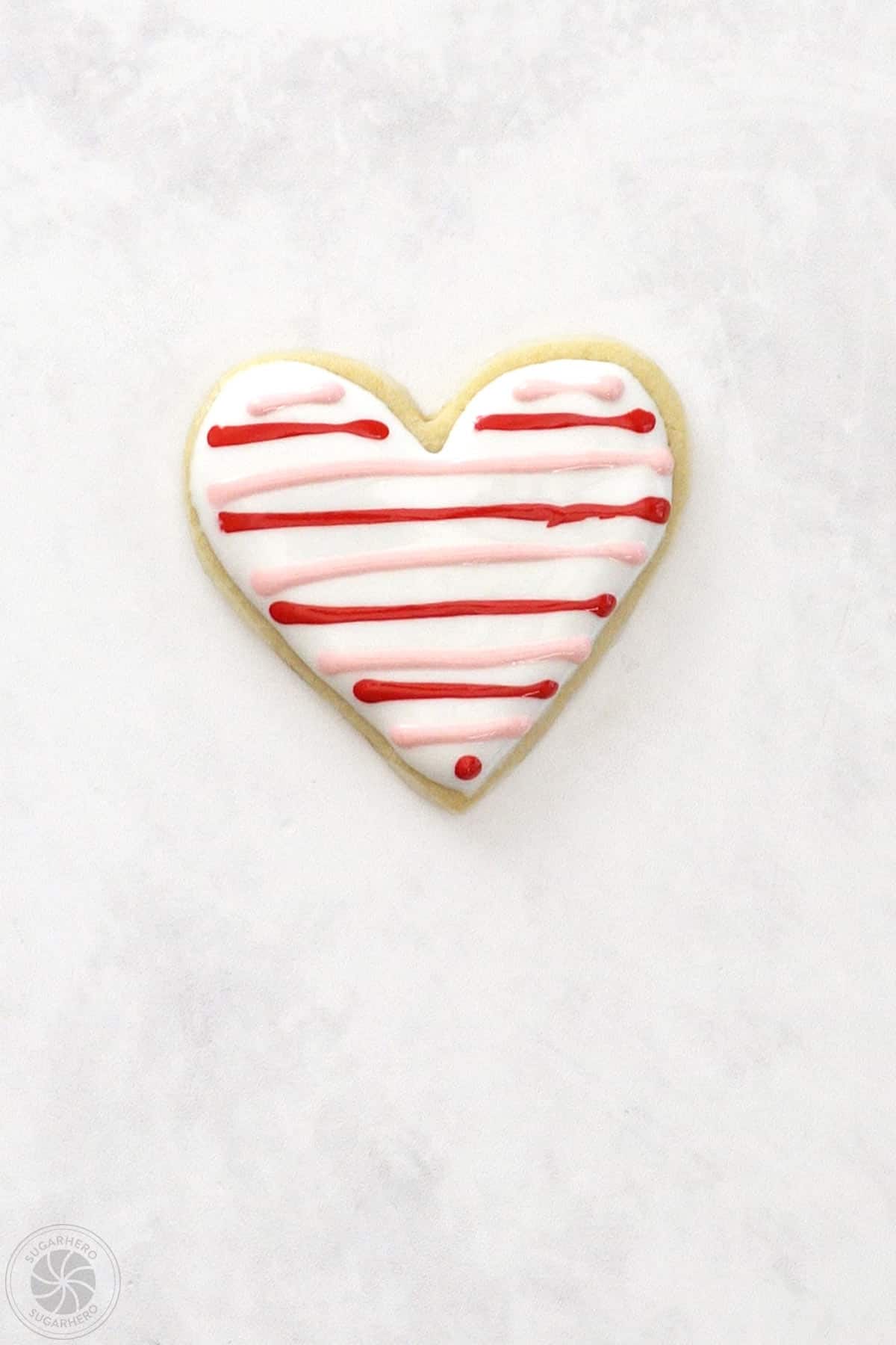 Valentine's Day Sugar Cookie with horizontal lines of red and pink royal icing.