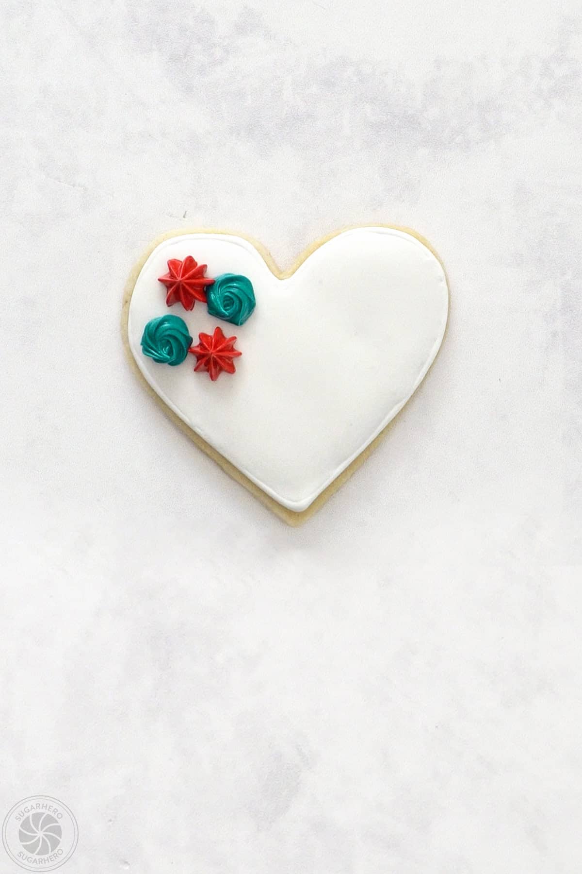 A Valentine's Day Sugar Cookie with 2 stiff piped rosettes and 2 red star shaped flowers.