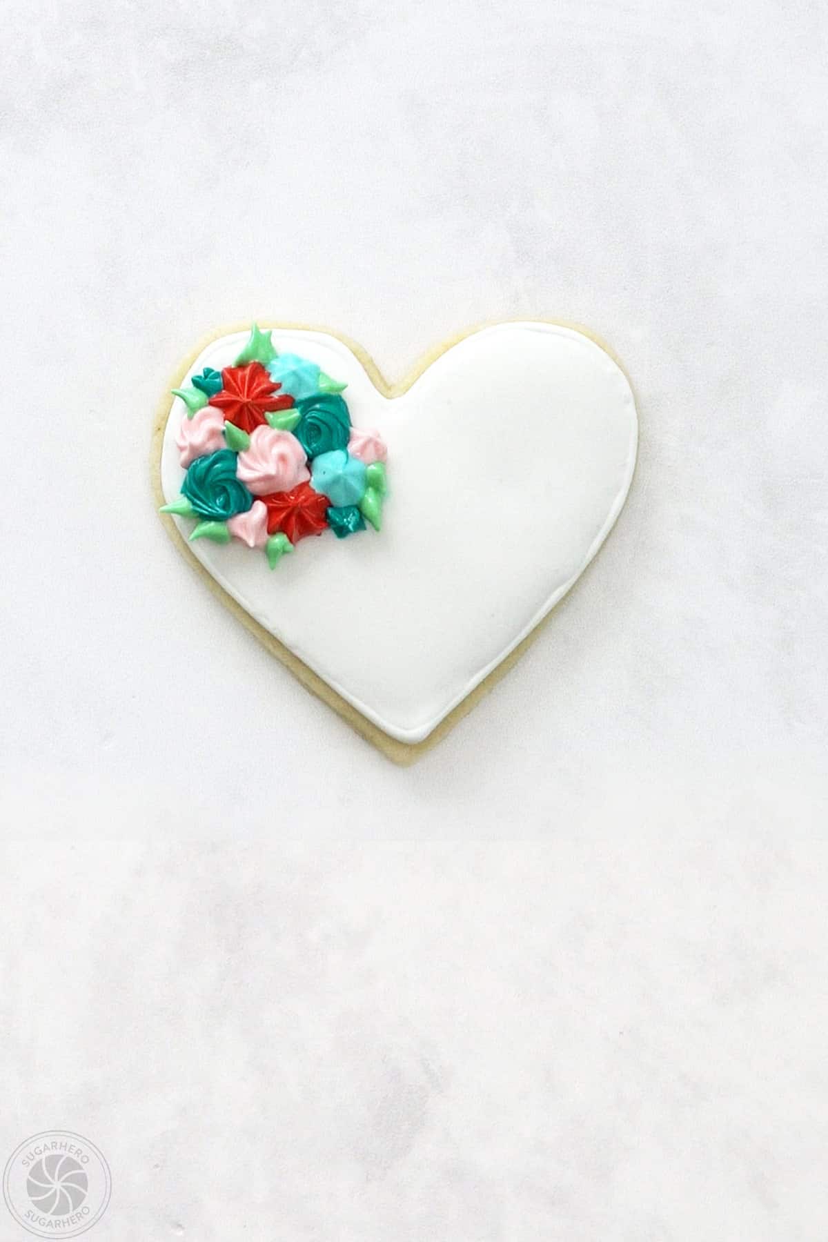 A Valentine's Day Sugar Cookie with an assortment of colorful stiff piped rosettes and green leaves.