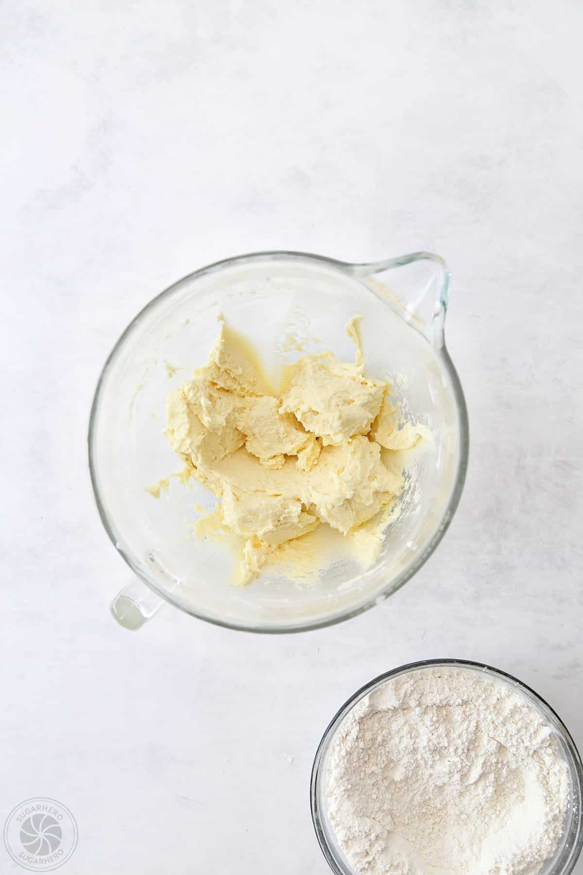 Creamed sugar cookie ingredients next to a bowl of the dry ingredients.