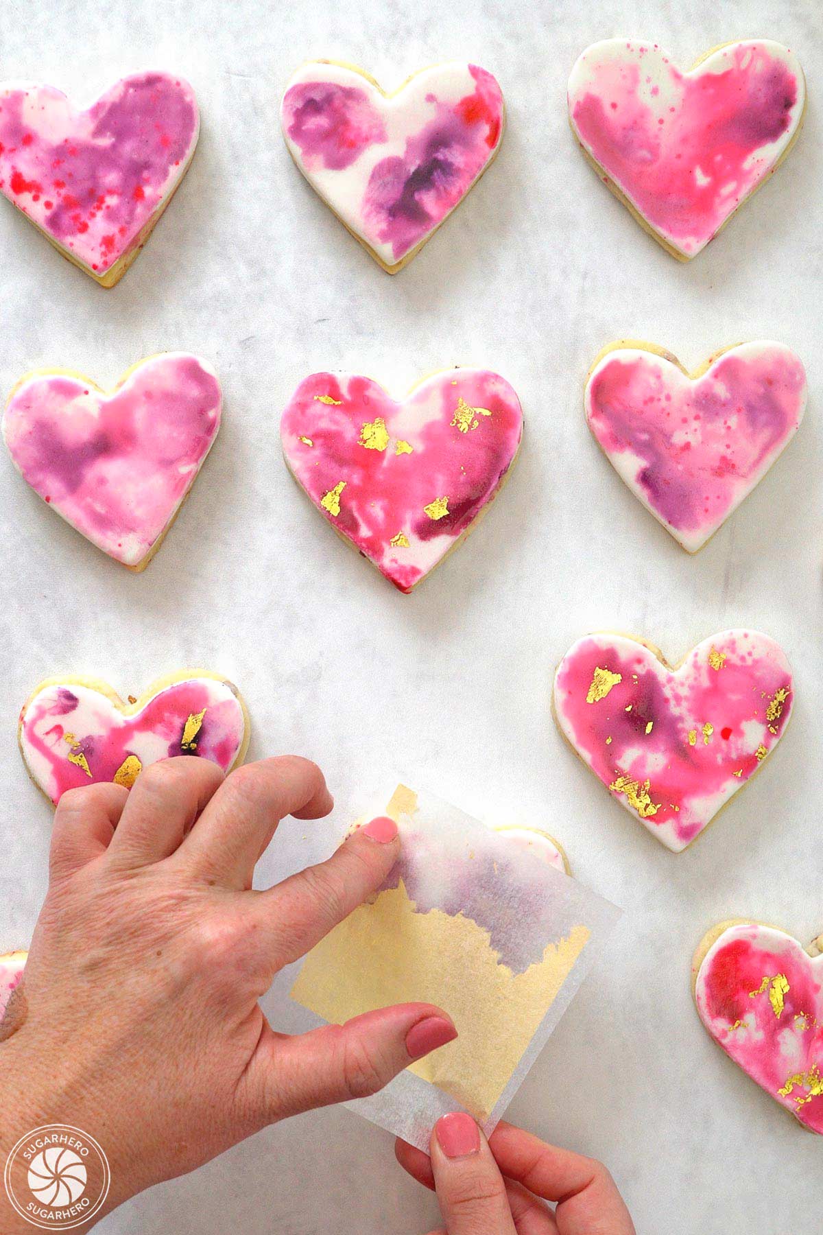 Hand transfering gold leaf onto watercolored sugar cookies.