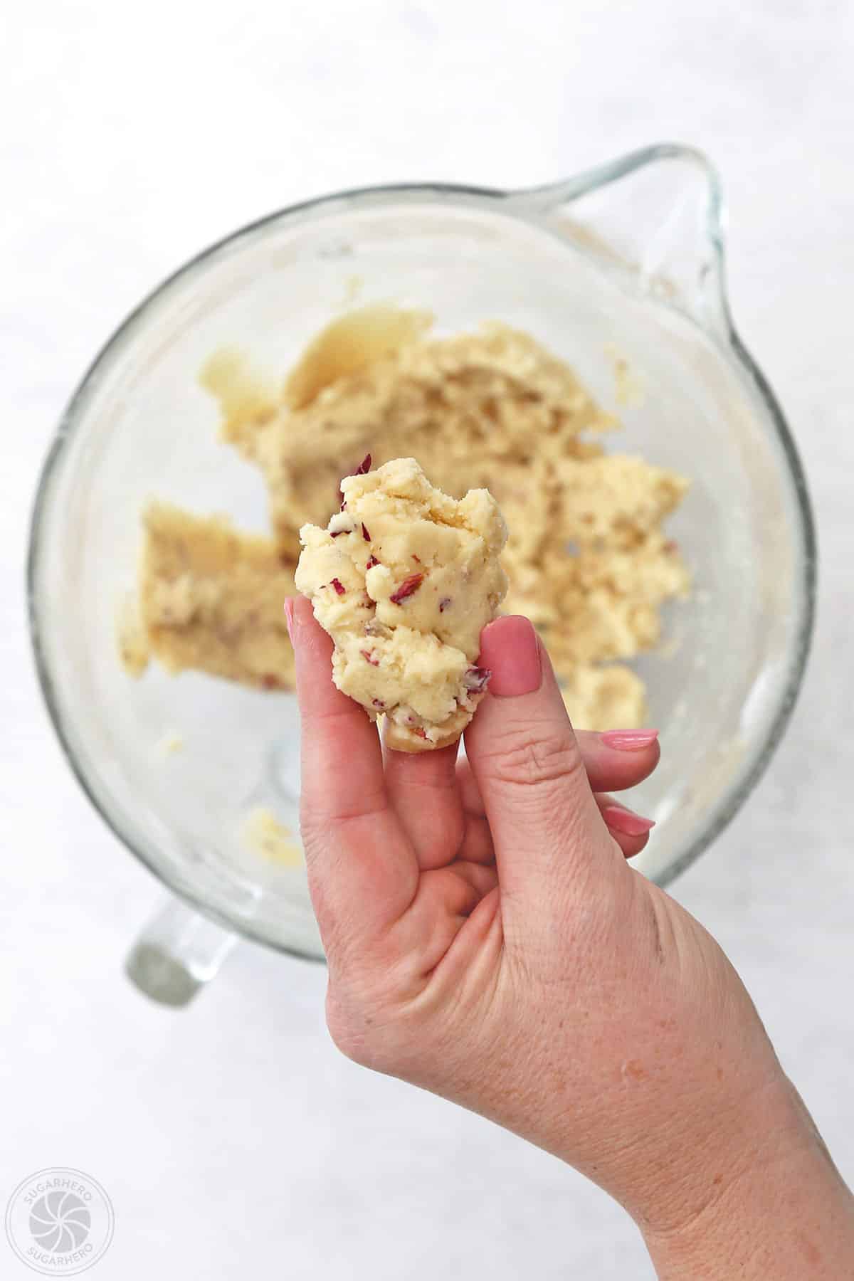 Hand holding up rose sugar cookie dough.