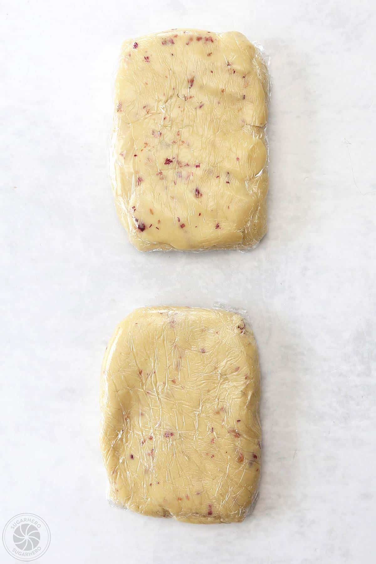 Two discs of rose sugar cookie dough wrapped in plastic.