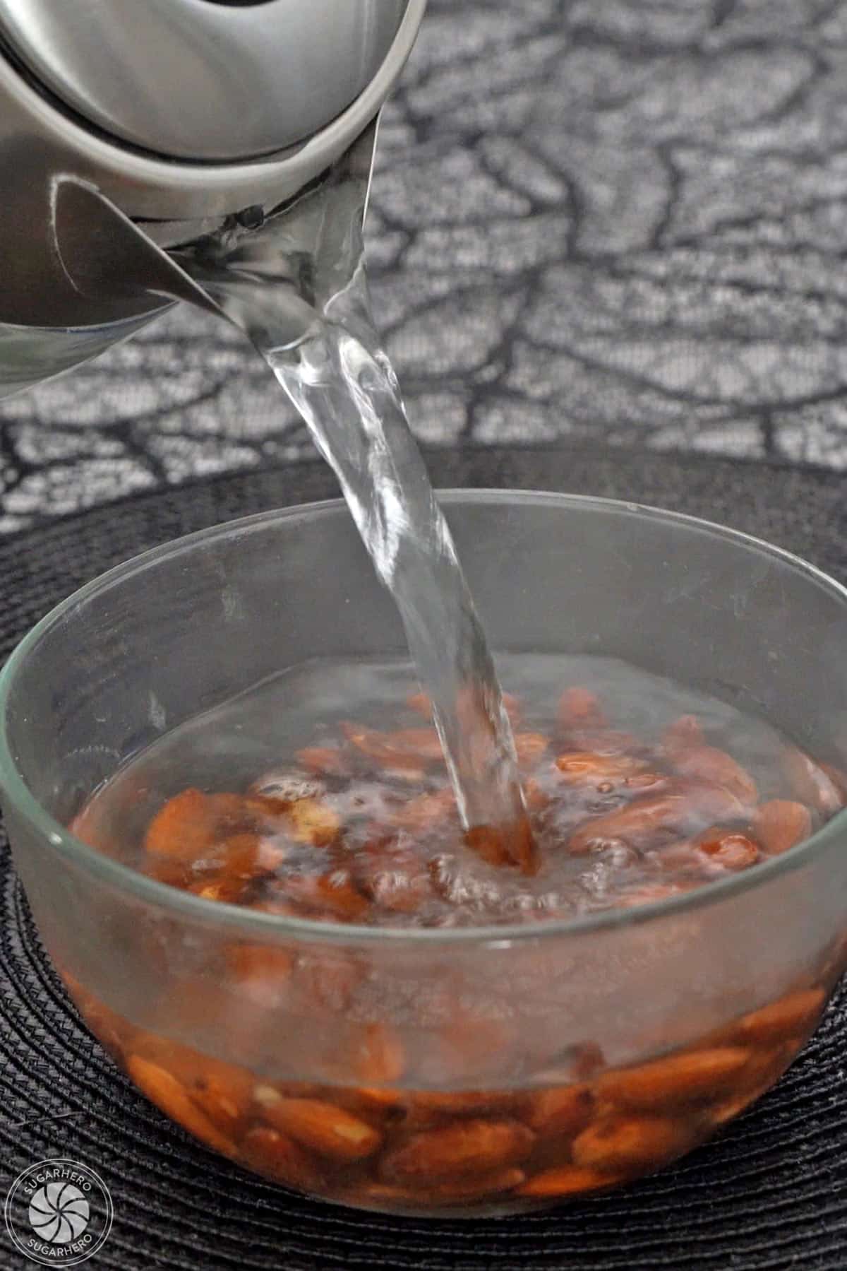 Pouring boiling water over almonds in a bowl.