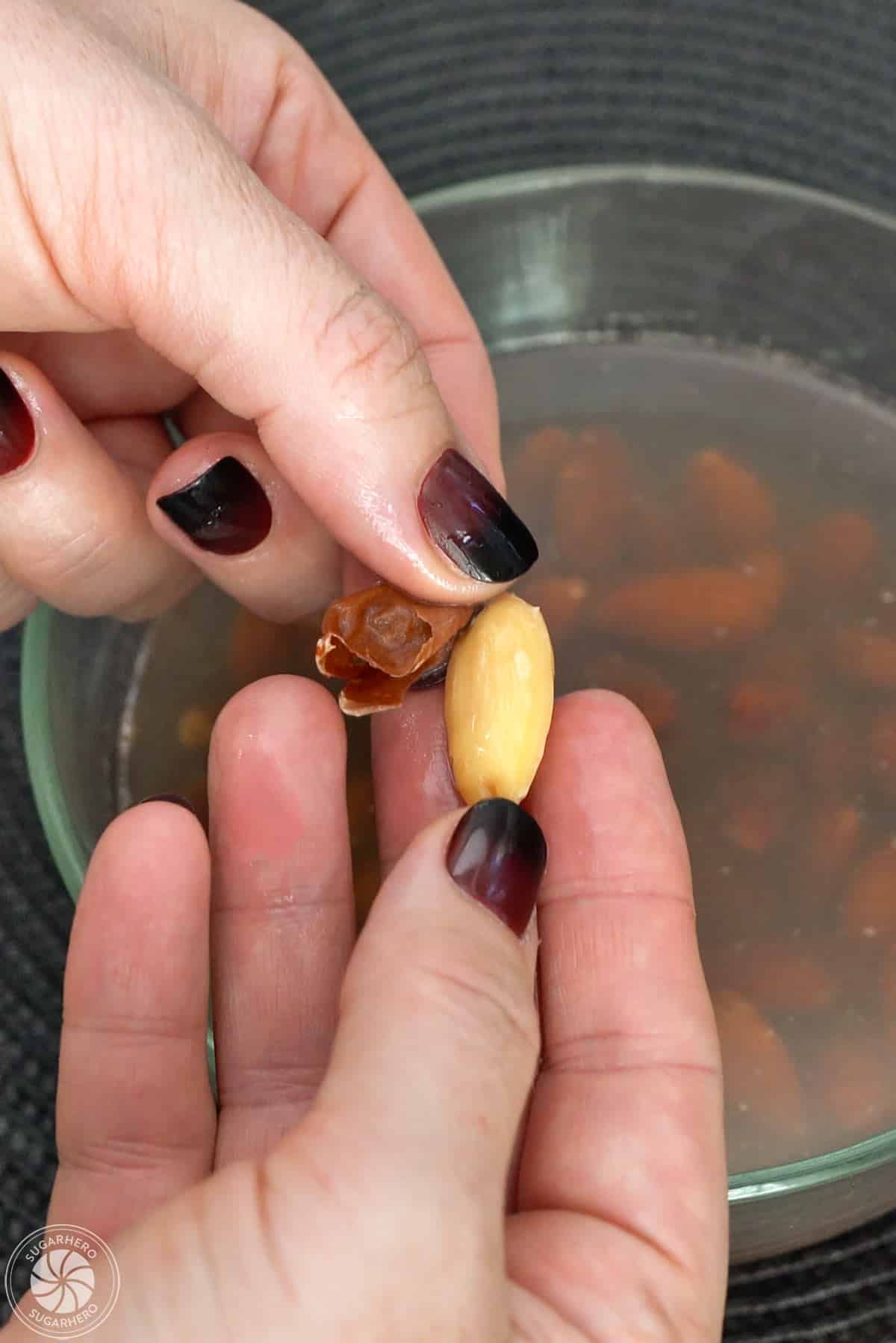 Peeling the almond skin off a blanched almond.