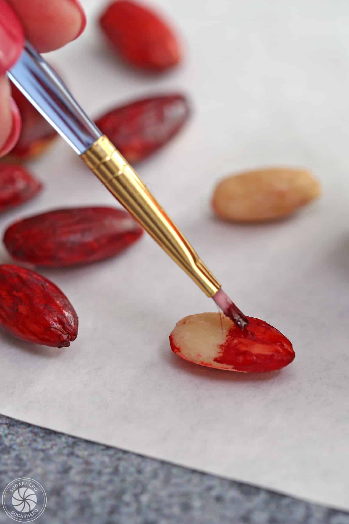 Painting a blanched almond with red food coloring.