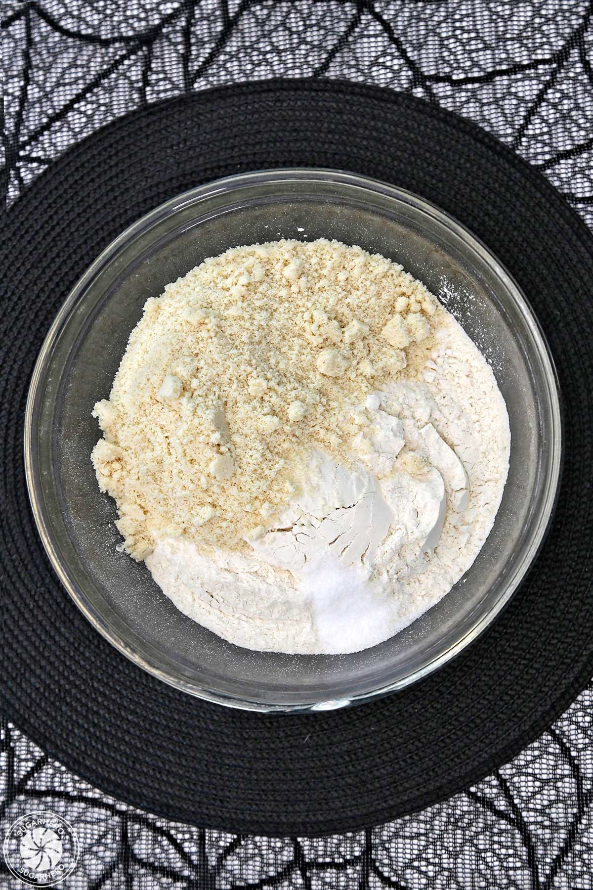 Overhead shot of almond flour and regular flour in a glass mixing bowl.