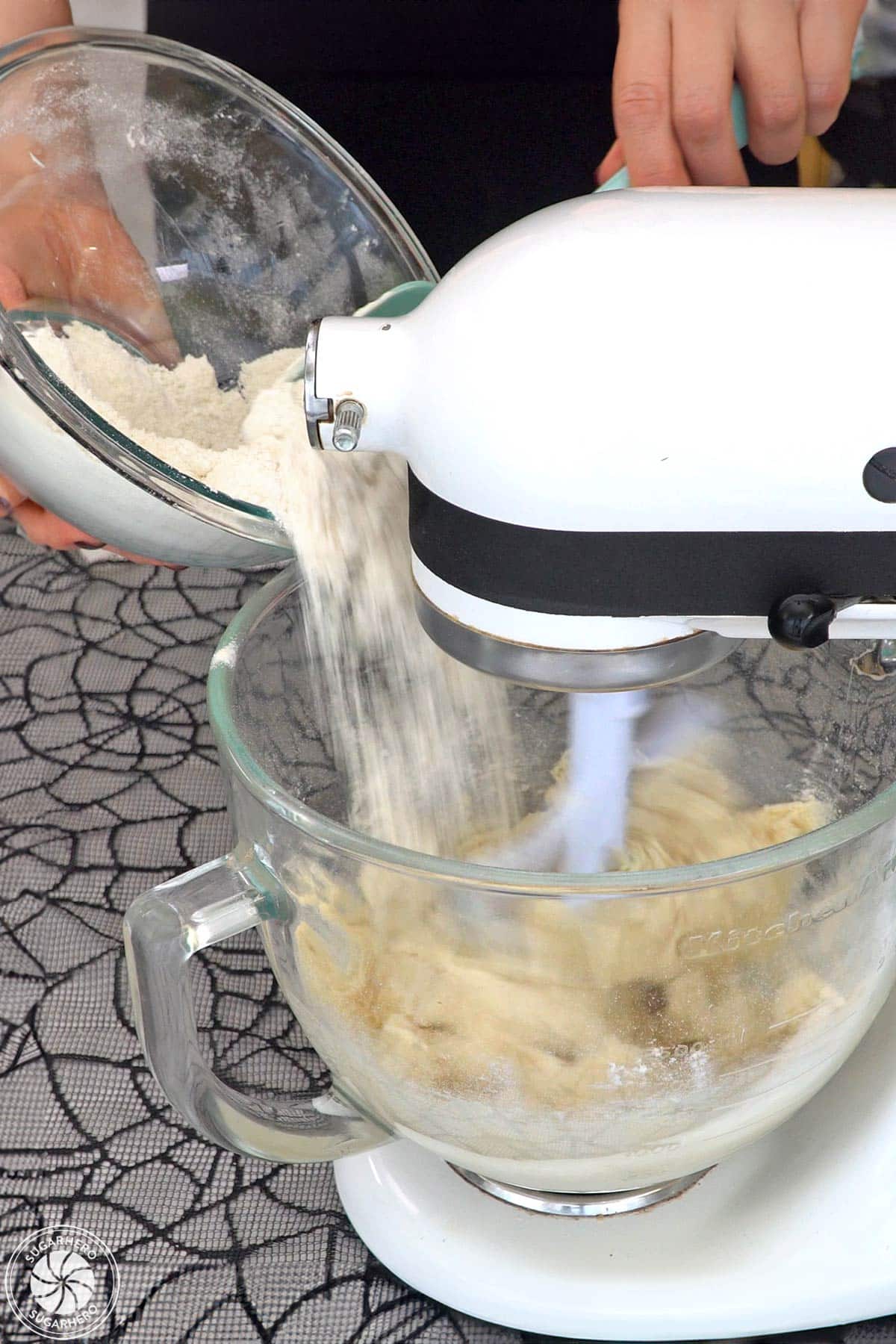 Pouring flour into glass mixing bowl to make witch finger cookies.