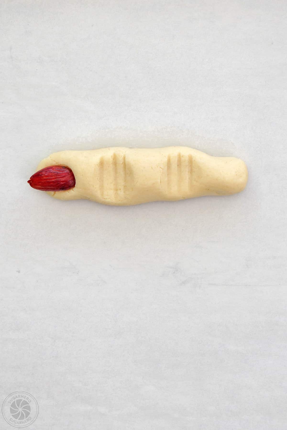 Red almond pressed into the top of a witch finger shortbread cookie.
